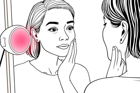 Line drawing of a woman in her 40s examining hyperpigmentation spots on her cheek with red light therapy for hyperpigmentation treatment nearby